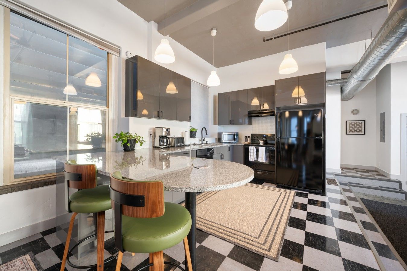 Una cocina moderna con una isla central, taburetes de bar e iluminación colgante.