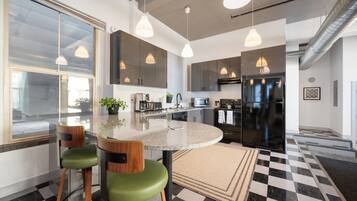 Una cocina moderna con una isla central, taburetes de bar e iluminación colgante.