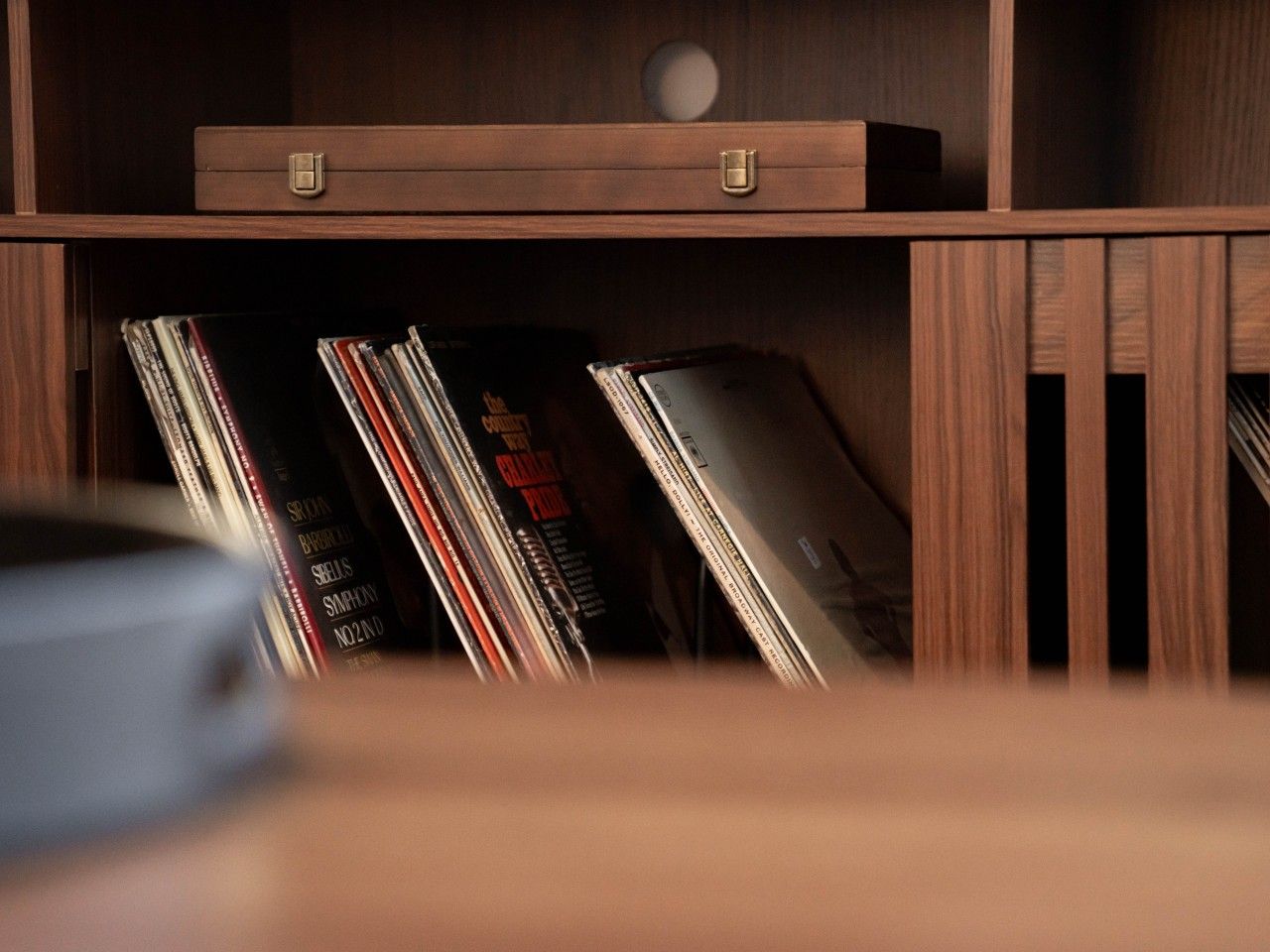 A wooden shelf with a closed drawer and a row of CDs or DVDs.