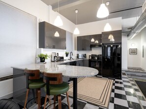 Una cocina moderna con una isla central, iluminación colgante y un piso con diseño de cuadros.