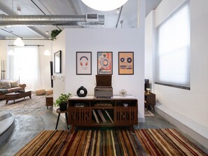 Una sala de estar moderna con una consola central, una obra de arte enmarcada en la pared y un tapete a rayas.