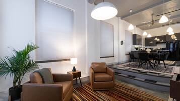 A modern living room with a sofa, armchair, and a dining area with a table and chairs.