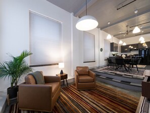 Een moderne woonkamer met een bank, fauteuil en een eethoek met een tafel en stoelen.