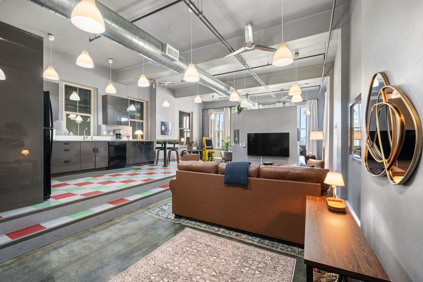 Un espacio habitable moderno con sofá, televisión y zona de cocina.
