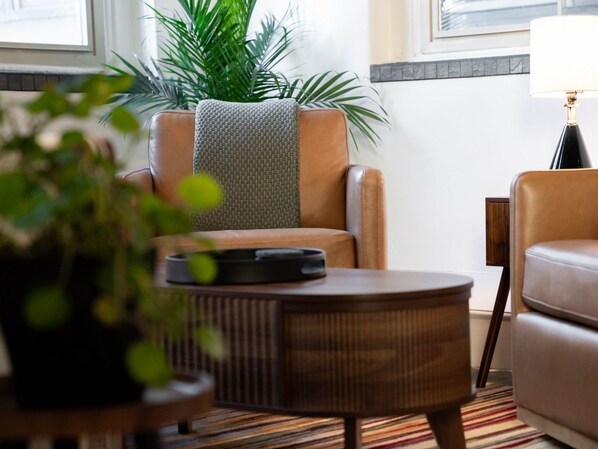 Una sala de estar moderna con un sofá de cuero, una mesa de centro redonda de madera y una planta en maceta.