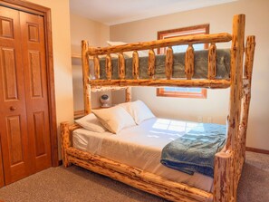 A wooden bunk bed with a headboard, a bedside table, and a window.