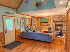 A cozy living room with a fireplace, a large sofa, and a television.