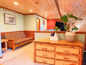 A wooden interior with a sofa, a wooden dresser, and a potted plant.