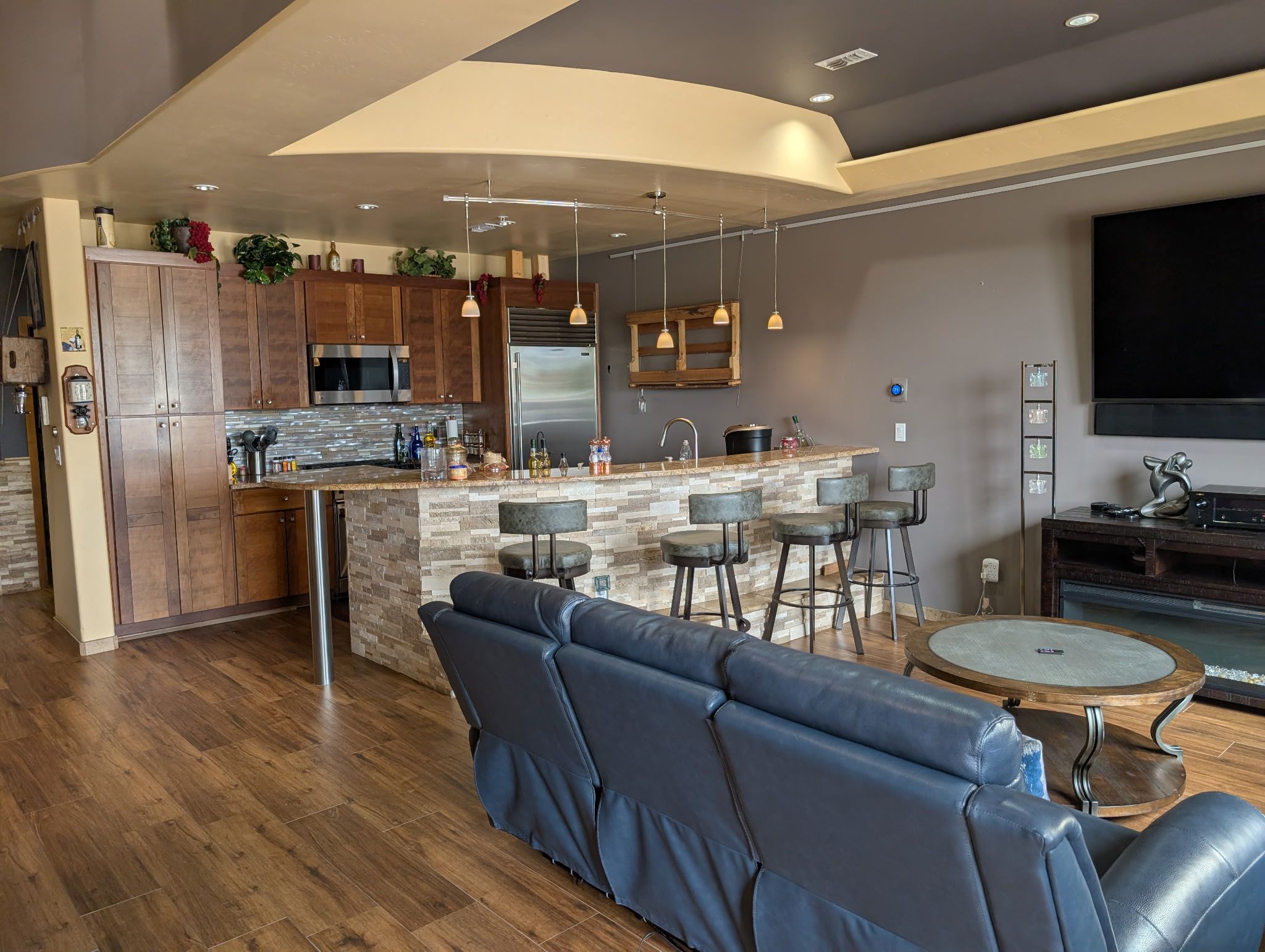 A modern kitchen with a central island, bar stools, and a built-in oven.