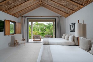 Ein Schlafzimmer mit einem großen Bett, einer Couch, einem Fenster und Blick ins Grüne.