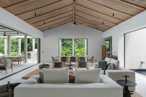 Ein modernes Interieur mit hoher Decke, großen Fenstern und einem Essbereich.