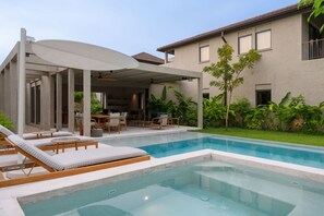 Ein moderner Poolbereich im Freien mit Liegestühlen und einer überdachten Lounge.