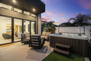 Eine moderne Terrassenanlage im Freien mit Whirlpool, Sitzbereich und einem verglasten Wohnbereich.