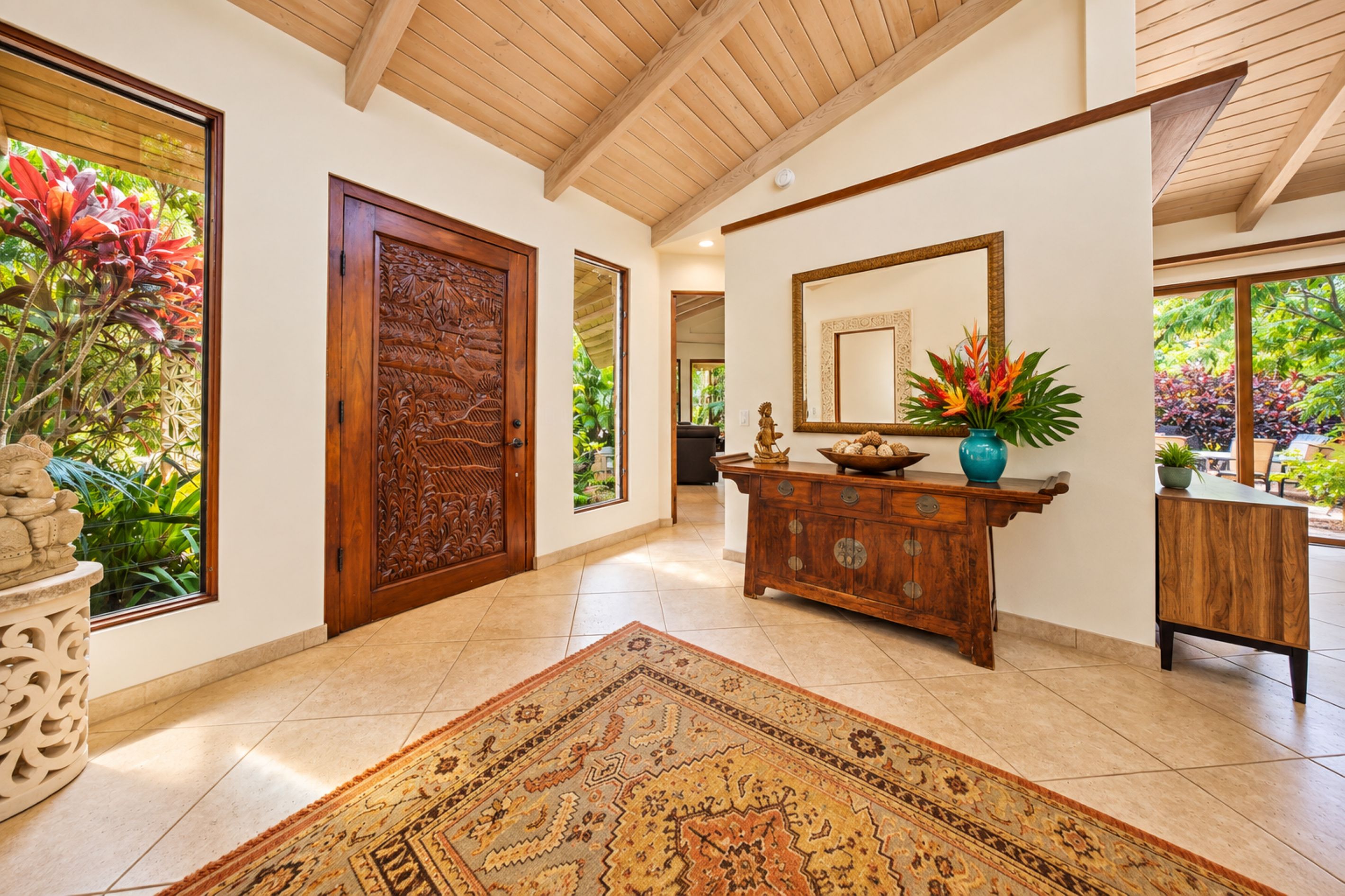 Un hall d’entrée spacieux avec une porte en bois, un grand miroir et un meuble décoratif.