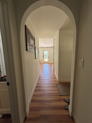 A hallway with wooden flooring, an arched doorway, and a framed picture on the wall. - 3-bedroom house close to the Canyons (Murray)