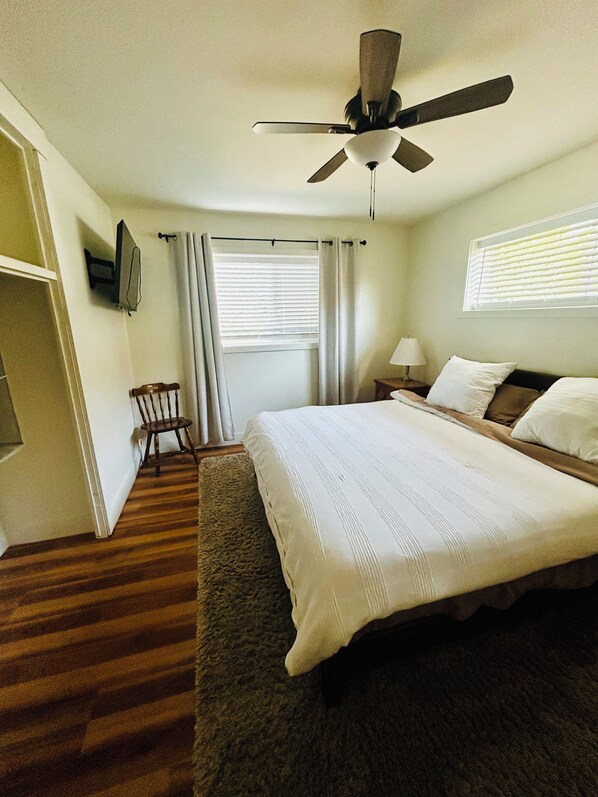A hotel room with a bed, a chair, a ceiling fan, a window with blinds, and a television on the wall. - 3-bedroom house close to the Canyons (Murray)