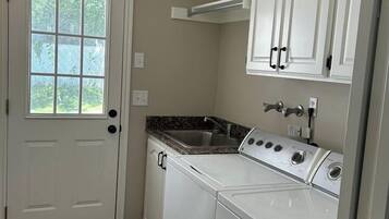 A laundry room with a washer and dryer, a sink, and a window.