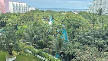 Un resort con piscina rodeada de exuberante vegetación tropical y edificios modernos al fondo.