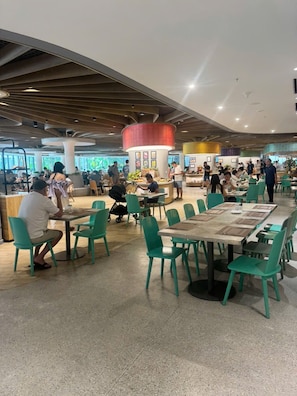 A spacious indoor dining area with multiple tables and chairs, a central serving station, and a modern ceiling design.