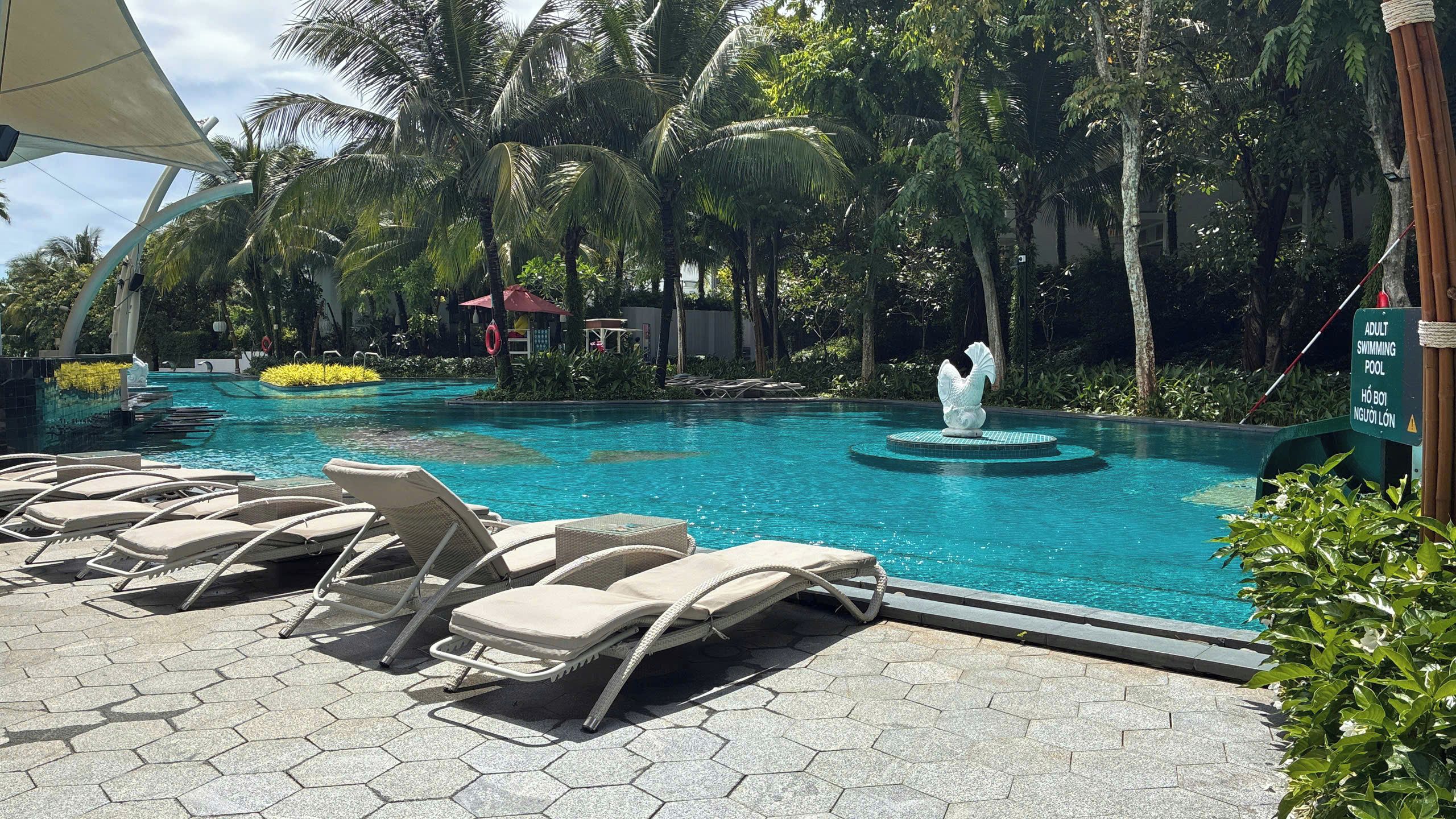 Una piscina con sillones de descanso y una fuente decorativa.