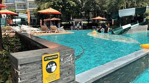 A swimming pool with lounge chairs and umbrellas, a children's pool, and a caution sign for supervision. - DIAMOND SUITE KEM BEACH (Phu Quoc)