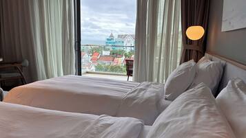 Quarto de hotel com duas camas, vista para edifícios e varanda.