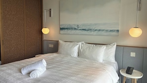 A hotel room with a bed, a painting of birds, and a phone on a bedside table. - DIAMOND SUITE KEM BEACH (Phu Quoc)