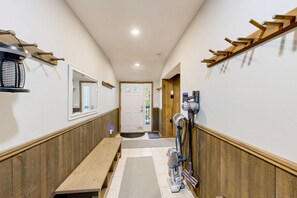 A hallway with a bench, a door, and a vacuum cleaner. - Winhall townhome with ski mudroom and Bromley slope views from the balcony (Winhall)