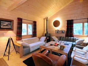 Interior d'una cabana acollidora amb un sofà, una taula de menjador i una llar de foc.