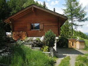 A wooden cabin with a stone foundation, a small shed, and a garden with various plants. - Chalet in Praz-de-Fort im Val Ferret by Interhome (Champex)