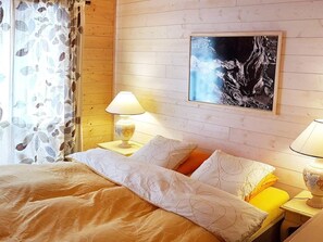 A bedroom with a bed, two bedside lamps, a painting on the wall, and a window with curtains. - Chalet in Praz-de-Fort im Val Ferret by Interhome (Champex)