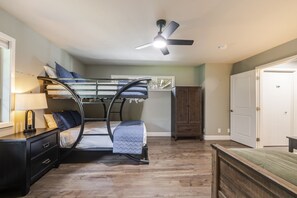 Ein Stockbett, ein Deckenventilator, ein Schminktisch, ein Schrank und eine Tür.