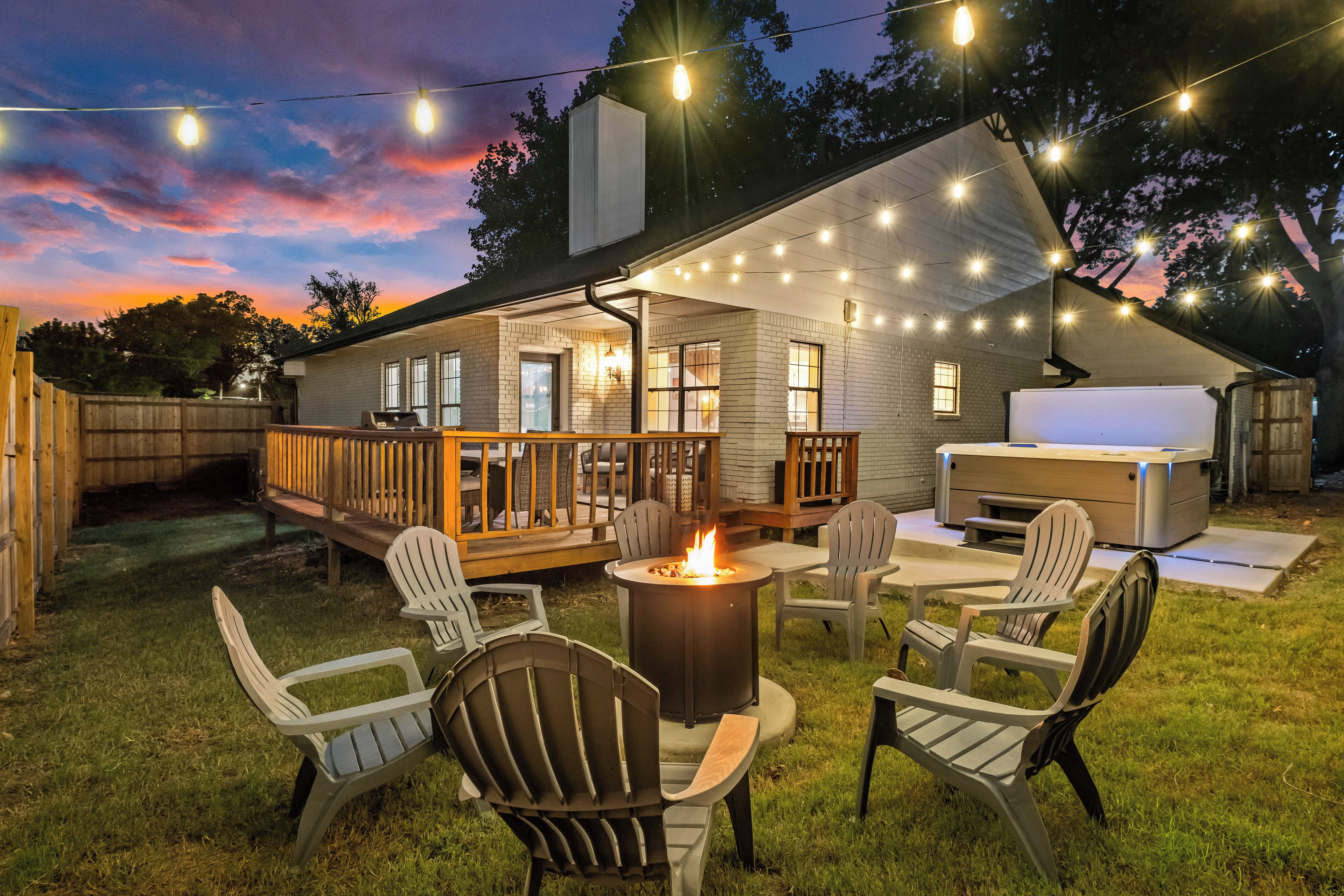 Ein Garten mit Feuerstelle, Sitzgelegenheiten im Freien und Lichterketten.