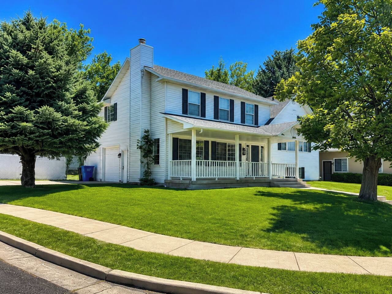 A two-story house with a covered porch, a garage, and a well-maintained lawn.