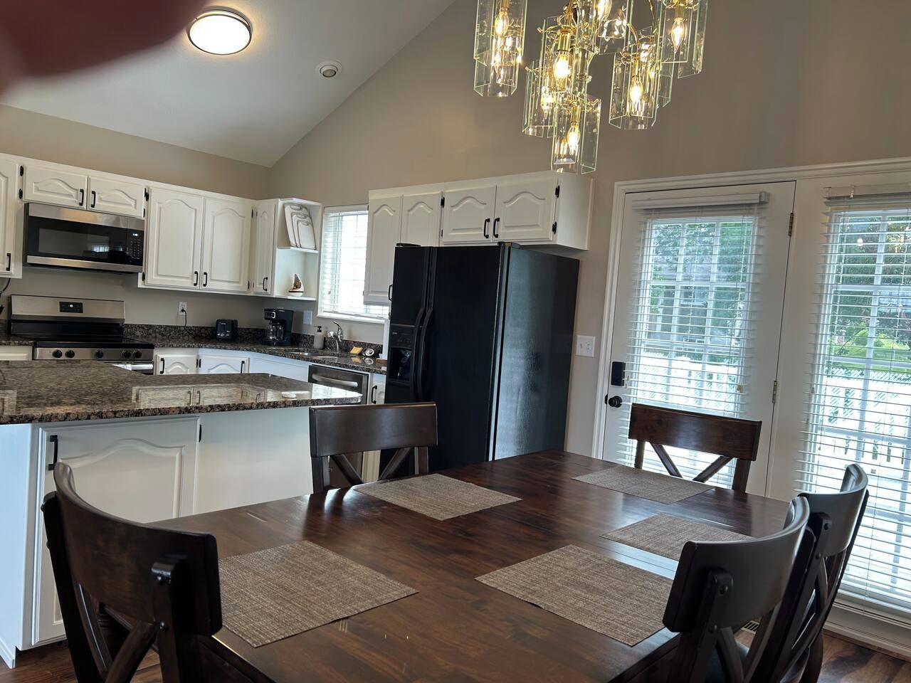 A kitchen with white cabinets, a black refrigerator, and a dining table with chairs.