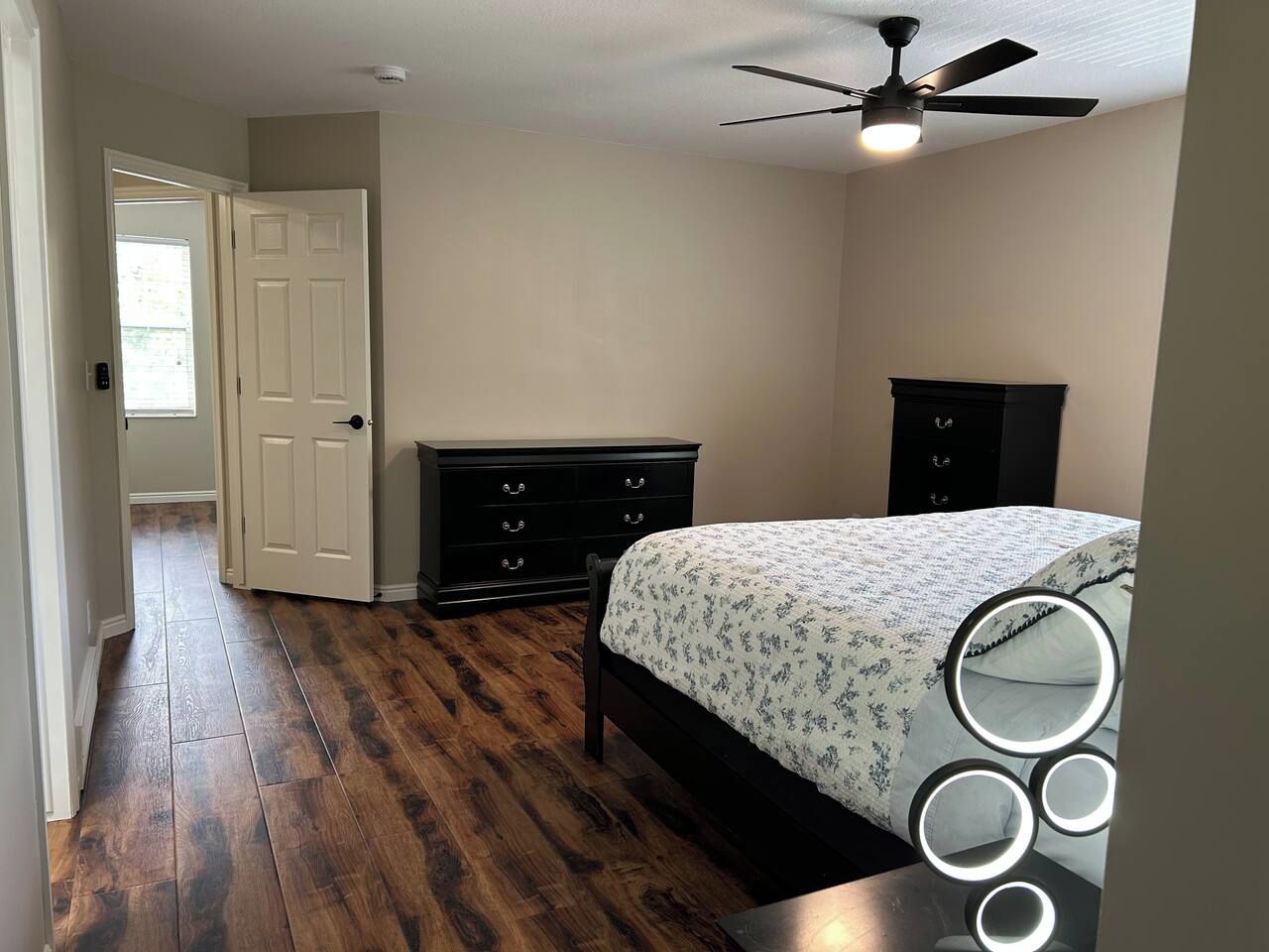 Ein Schlafzimmer mit Bett, Schminktisch und Deckenventilator.