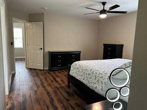 Ein Schlafzimmer mit Bett, Schminktisch und Deckenventilator.