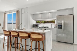 Fully equipped kitchen with modern appliances and a spacious breakfast bar featuring seating for four. - Brand New 3BR Villa | Pool, BBQ & Lighthouse View (Noord)