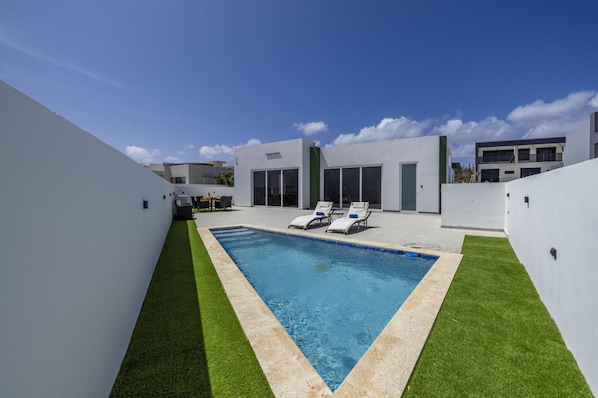Your private backyard paradise—soak up the sun on comfortable loungers or take a refreshing dip in the crystal-clear pool. - Brand New 3BR Villa | Pool, BBQ & Lighthouse View (Noord)