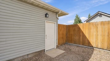 A residential property with a garage door, a wooden fence, and a gravel driveway.