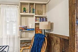Ein Zimmer mit einem Bücherregal, einer Lampe, einem Sessel und einem Schild mit dem Wort 'GATHER'.