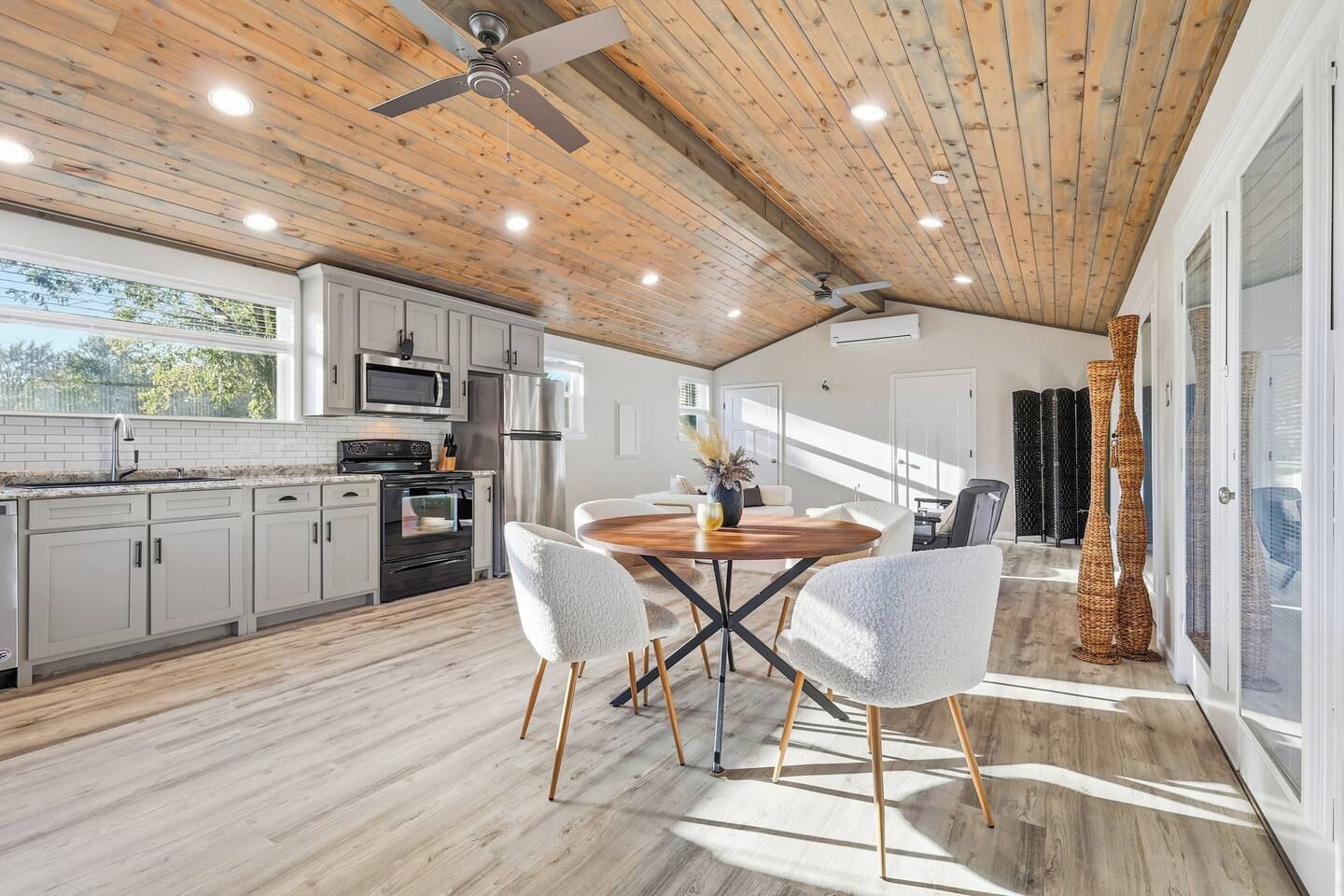 A modern kitchen with white cabinets, a central island, and a ceiling fan.