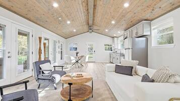 A spacious living area with a high ceiling, a dining table, and a kitchen area with modern appliances.