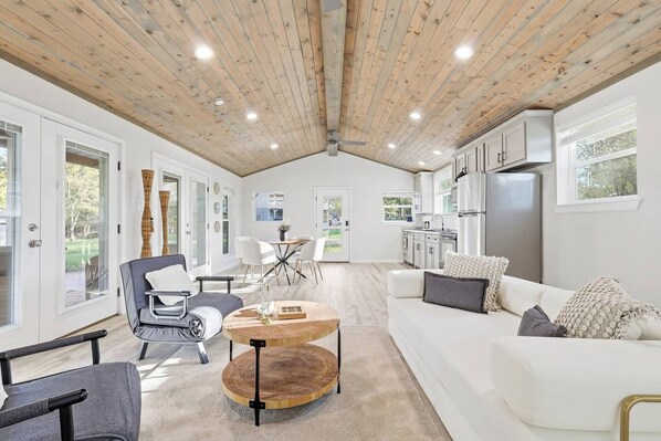 A spacious living area with a high ceiling, a dining table, and a kitchen area with modern appliances.