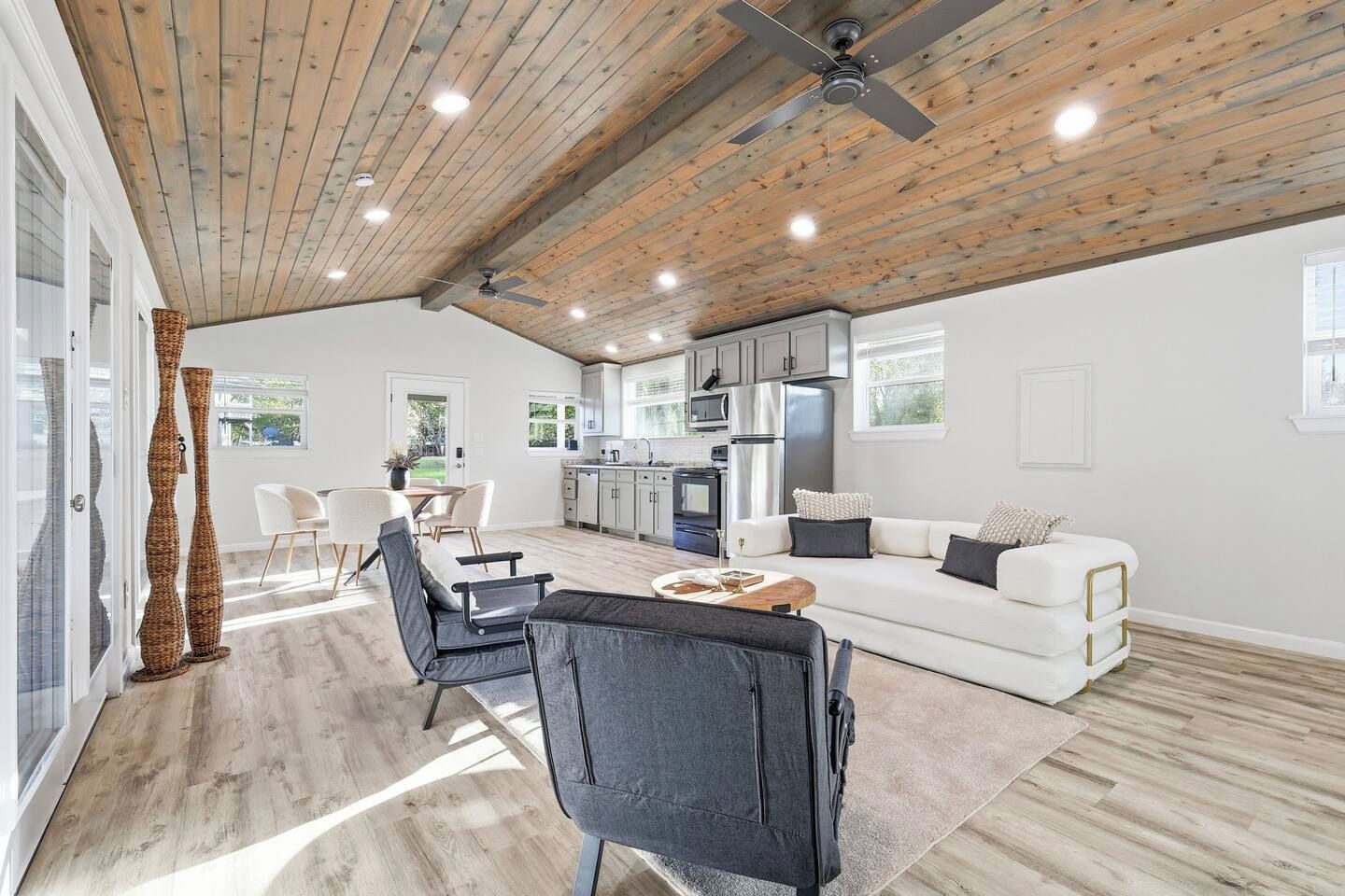 A modern kitchen with white cabinets, a stainless steel refrigerator, and a dining area with a table and chairs.