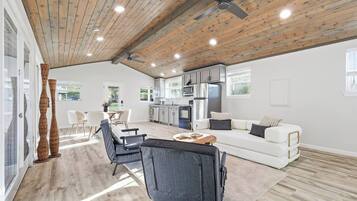 A modern kitchen with white cabinets, a stainless steel refrigerator, and a dining area with a table and chairs.