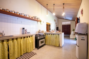 A kitchen with a stove, oven, and a refrigerator. There is a sink and a countertop with various kitchen items. - House with a pool 350 m from Peroba Beach (Maragogi)