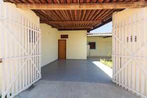 A corridor with a wooden door at the end, leading to a room with a tiled floor. - House with a pool 350 m from Peroba Beach (Maragogi)