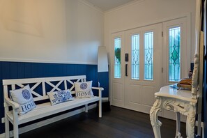 A room with a white bench, a white table, and a door with glass panels. - Blu Bay View—Stroll Down to the Bay at Golden Hour (Geographe)