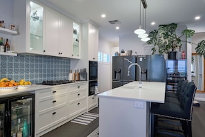 A modern kitchen with white cabinetry, a central island, and a black refrigerator. - Blu Bay View—Stroll Down to the Bay at Golden Hour (Geographe)